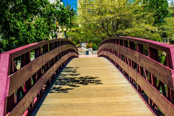 Wooden Walking Bridge Over River Leading To Downtown Area