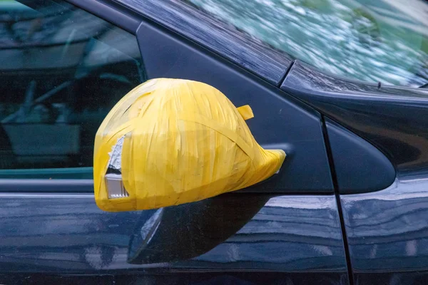 Dikiz aynası arabada teyp siyah araba, sarı koli bandı ile onarım..