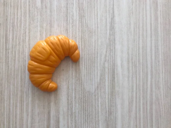 Ein Plastikspielzeug Croissant Auf Dem Hölzernen Hintergrund — Stockfoto