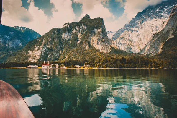 View to St. Bartholomew\'s Church and mountains from a boat on the Koenigssee lake, Germany