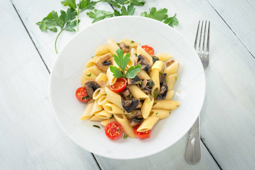 Dish of penne pasta with mushrooms and cherry tomatoes, mediterranean food 