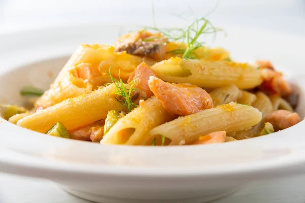Plate of italian pasta with cooked salmon, courgettes and bottarga