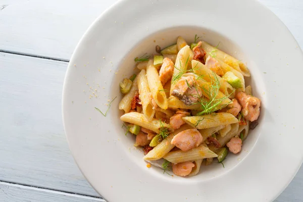 Dish of italian penne pasta with salmon, courgettes and bottarga