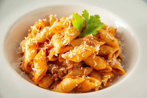 Dish of italian mezze penne pasta with ragout sauce and cheese