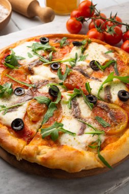 Mozzarella, domates sosu, zeytin, hamsi ve roka salatası ile lezzetli dilimlenmiş sıcak pizza 