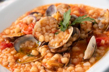Fregula, tipik bir sardunya makarnası, istiridye ve domates soslu, İtalyan mutfağı. 