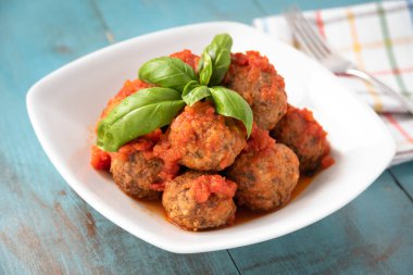 Bir tabak lezzetli köfte, domates sosu ve taze fesleğen. 