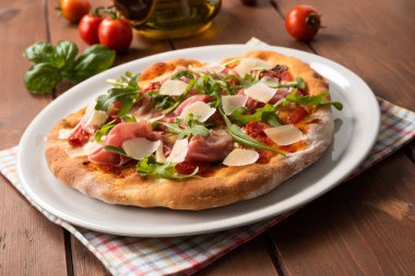 Prosciutto, grana, roket ve domates soslu nefis İtalyan pizzası. 