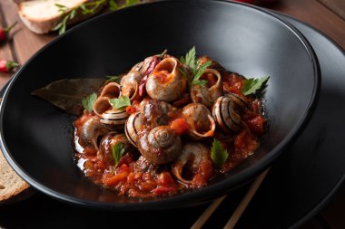 Baharatlı domates soslu lezzetli salyangoz tabağı, kırsal İtalyan yemeği.