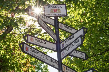 Çok yön işareti kentin Nüfus gelişimi ve kız kardeşi Uzaklik gösterilen Gdansk şehirler. Tabelasını orman ve ağaç içinde belgili tanımlık geçmiş. Güzel bir gün ve yaz duygu.