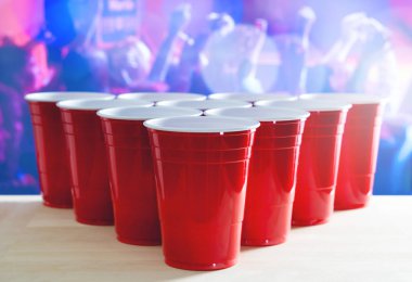 Bira pong turnuva düzeni. Fazla kırmızı parti bardak arka planda dans pistinde dans insanlarla dolu bir gece kulübünde. Pazarlama ve promosyon için olay için idealdir. Ahşap masa üzerinde plastik kupalar