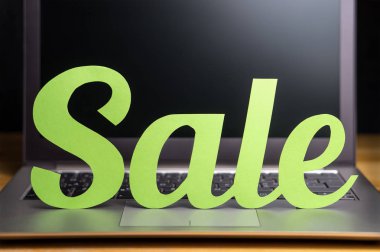 Satılık reklam online mağaza. Tanıtım ve pazarlama afiş bir internet Mağazası için. Işık yeşil karton harfler dizüstü bilgisayarda karton kağıt kesti. Hareketli ve cathcy alışveriş ve e-ticaret tasarım.