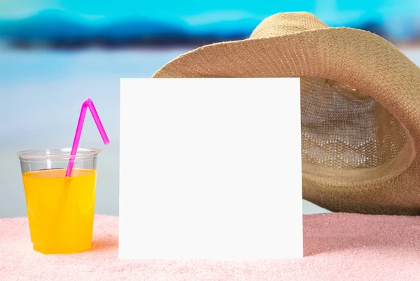 Summer offer background template for promotion and sales. Yellow cocktail and brimmed hat on towel with beautiful paradise view on beach. Empty white paper card with free blank copy space for content.