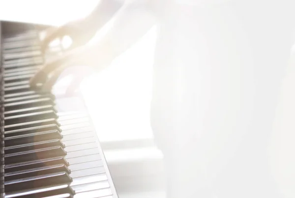 Blurry abstract music background. Wallpaper for piano lessons, training, coaching and talent show with free empty blank copy space for text. Man playing instrument. Yellow lens flare from sun light.