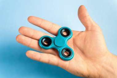 Mavi arka plan ile topluca spinner tutan el.