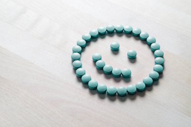 Gülen yüz hapları ahşap masa üzerinde. Başarılı şifa dan mutlu ve olumlu duygu işlemek veya sağlık ve Doktor Hizmetleri ile memnun. Doğru ilaç veya şu tıbbi tedavi.