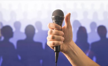 Mikrofon tutan ve gösterilen el başparmak yukarıya siluet kişilik bir kalabalık önünde. Kamu konuşma ve veren konuşma kavramı. Mikrofon, iyi karaoke veya başarılı yetenek gösterisi için de canlı şarkı.