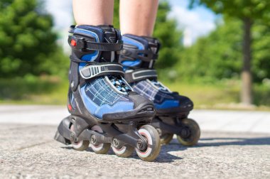 Yaz aylarında paten. Mavi rollerskates asfalt ve asfalt güneşli. Şehrin asfalt üzerinde paten. Eğlenceli serbest zaman etkinliği. Doğa, ağaçlar ve ormanlar içinde belgili tanımlık geçmiş.
