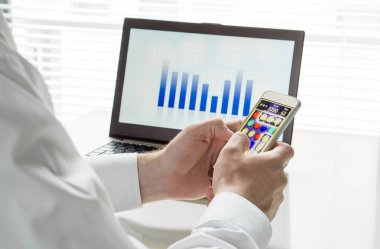 Tembel ve verimsiz İşyeri işçi çalışma saatleri içinde smartphone telefon oyun oynuyor. İçinde belgili tanımlık geçmiş laptop ve iş rakamlar ile işini görmezden. İşe yaramaz çalışan.