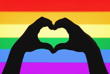 Kalp gösterilen eller eşcinsel gurur ve Lgbt gökkuşağı bayrağı üzerinde oturum açın. Cinsel azınlık, eşcinsellik ve eşit haklar kavramı. Renkli arka plan aşk sembolü silüeti.