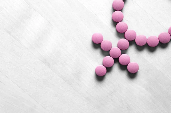 Medicine for woman. Menopause, pms, menstruation or estrogen concept. Female health. Gender symbol made from pink red pills or tablets on wooden table.