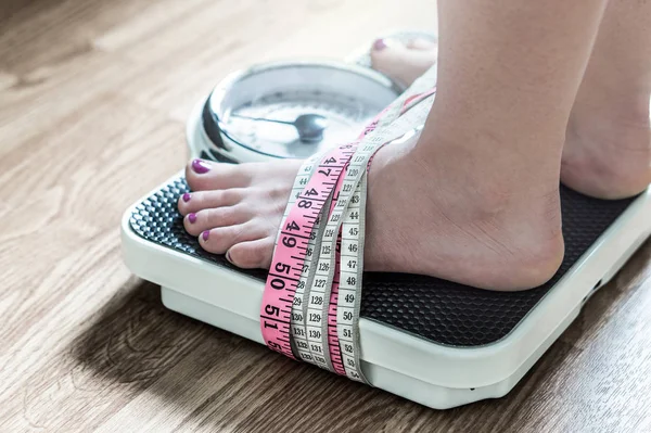 stock image Feet tied up with measuring tape to a weight scale. Addiction and obsession to weight loss. Anorexia and eating disorder concept.