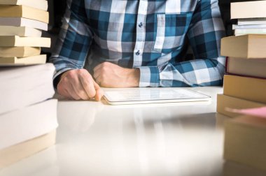 Elektronik kitap ya da online haber okuyucu ile okumak adam. Tablet veya akıllı mobil aygıt tarafından kitap yığınları çevrili yaptırın.