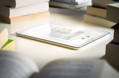 Elektronik kitap okuyucu. Geleneksel kitap yığını tarafından çevrili okumak için modern akıllı aygıt. Kitaplık veya ana sayfa.