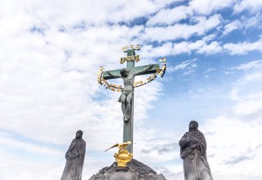 İsa boyutlarda heykellere uygulayan çarmıhta asılı. INRI heykel mavi kısmen bulutlu gökyüzü karşı.