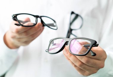Lensler karşılaştırıldığında veya müşteri farklı seçenekler gözlük içinde gösterilen gözlükçü. Göz doktoru gösteren yeni gözlük. Birçok gözlük ile Beyaz paltolu profesyonel göz doktoru.