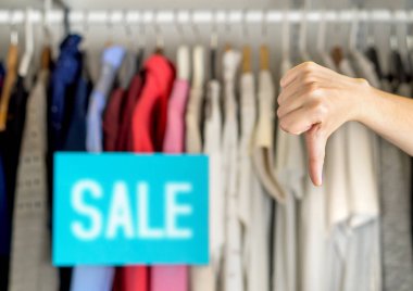 Mutsuz ve hoşnutsuz müşteri, kötü hizmet veya ürün kalitesi için bir giyim mağazasında başparmağını kaldırıyor..