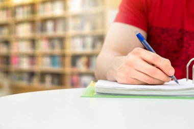Young athletic man and student studying and writing notes in public or school library in college or university. Stack and pile of books, pen and paper on table. Negative copy space. clipart