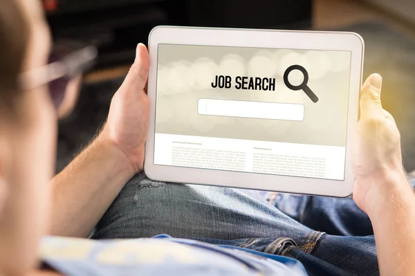 Man trying to find work with online job search engine on tablet. Jobseeker at home holding smart device. Motivated and happy applicant. Modern job hunting, seeking and unemployment concept.