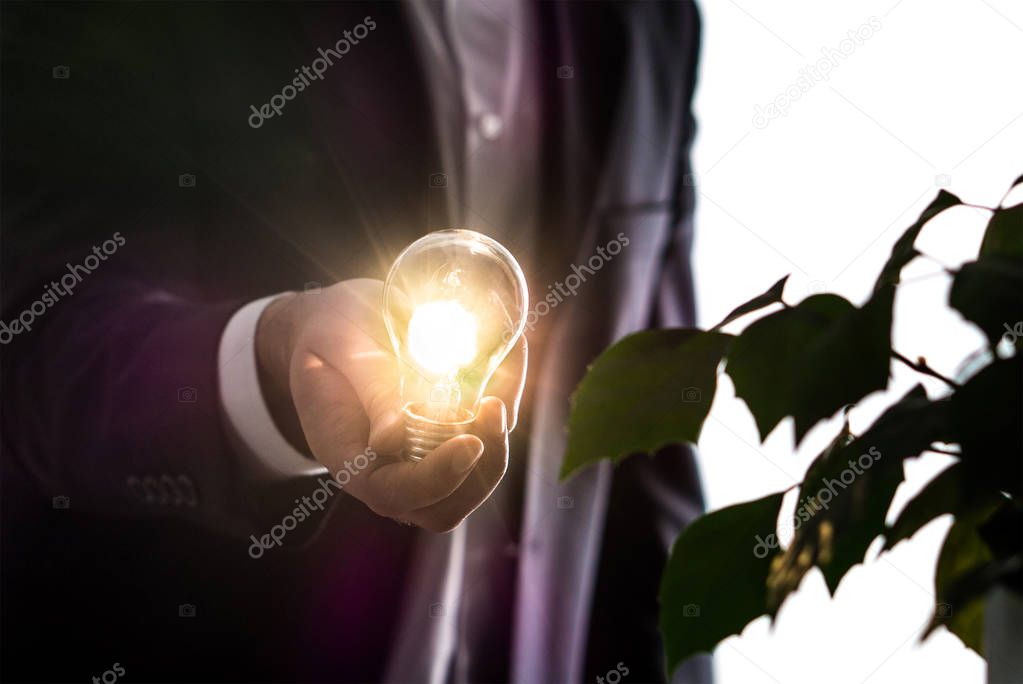 Businessman or man in a suit holding an illuminated light bulb in hand. Innovation, brainstorming and creativity concept. Environmental lawyer with an idea.