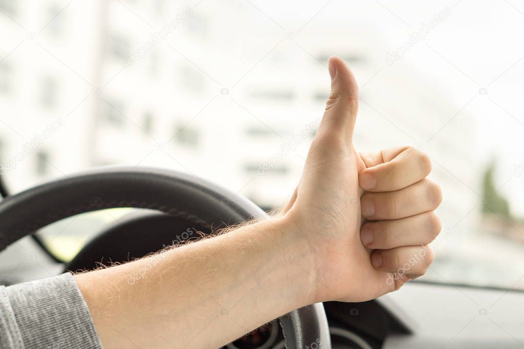 Happy driver showing thumbs up in car. Satisfied with new car or no traffic. Passed driving school test or vehicle inspection. Vehicle fixed and repaired.