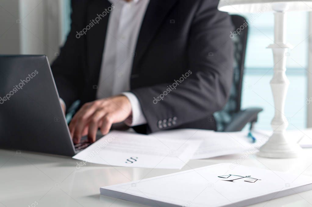 Scale and justice sign on pile of paper. Lawyer working in office. Attorney writing a legal document with laptop computer. Law firm and business concept.