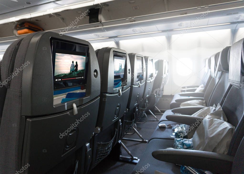 Seats waiting for passengers and take off in an airplane. Empty plane interior before flight and departure. Watching movie on an aircraft. Imaginary film playing on a video player in monitor.