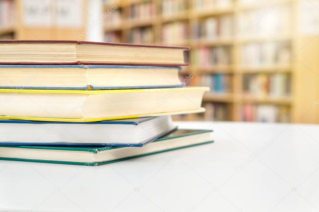 Stack and pile of books on table in public or school library. Education, studying and literature service concept with negative copy space.
