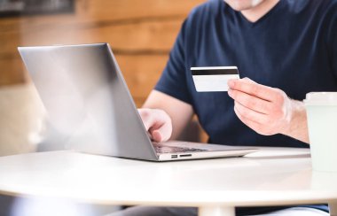 Kredi kartı holding ve banka bilgileri veya kimlik numaraları ile laptop yazmaya adam. E-ticaret ve online alışveriş kavramı.