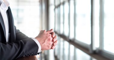 Düşünme ve pencereden dışarı bakarak iş adamı. Eğilerek ellerini yakın çekim.