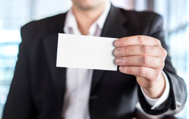 Boş beyaz kartvizit modern ofis binası içinde holding iş adamı. Ücretsiz boş kopya alanı.