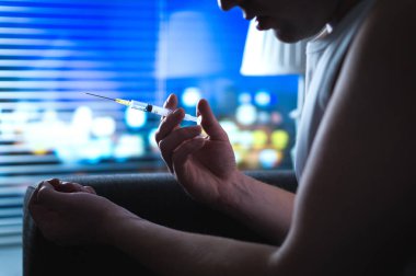 Eroin bağımlısı uyuşturucu kullanarak gece geç karanlıkta. Kirli iğne kullanarak kötü uyuşturucu sorunu olan genç adam. Dramatik bağımlılığı, aşırı doz ve madde bağımlılığı kavramı. Yoksunluk belirtileri.