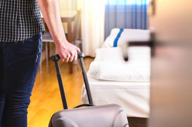 Bavul çekerek ve otel odaya giren bir adam. Odasına giriyor veya Bagaj Motel'i içinde yürüyüş gezgin. Seyahat ve tatil daire kiralama kavramı.