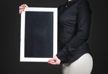 Garson holding boş yazı tahtası. Boş yazı tahtası ile siyah gömlekli genç profesyonel kadın. Negatif kopya alanı restoran menü, café özel veya mutlu saatler için bir barda fırsatlar. Koyu arka plan.
