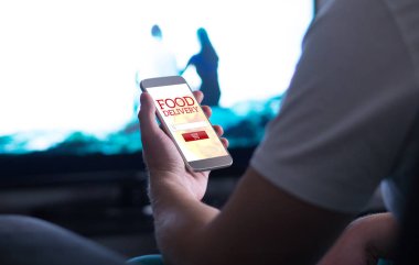 Yiyecek sipariş online teslimat app ve smartphone ile götürün. Tv izlerken pizza veya lokanta ev satın adam.