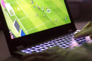 İskambil video oyun dizüstü bilgisayar ile genç adam. Online futbol ya da futbol oyun içinde bilgisayar. El üstünde bilgisayar klavye yakın çekim.