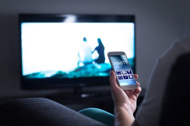 Televizyon izlerken ve cep telefonu akıllı tv uzaktan kumanda uygulaması kullanarak adam. Film akışı seçerek, kanal değiştirme veya smartphone ile menü ve Kullanıcı arabirimi ayarlarını değiştirme.