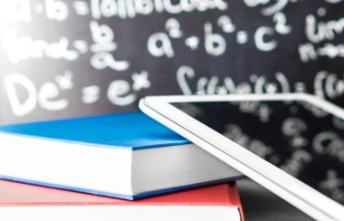 E öğrenme ve modern eğitim kavramı. Akıllı hareket eden aygıt ve tablet ile bir tahta okul önünde renkli kitap yığını. Internet üzerinde eğitim veya online öğretim. Dijital kitap okuyucu.