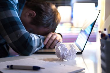 Gece eve ya da modern iş ofiste üzgün ve yorgun bir adam. İşsiz iş arayan veya yırtık kağıt ve masa üstünde laptop ile işadamı. Motivasyon ya da ilham yok. Yazar tıkanması veya fikirler.