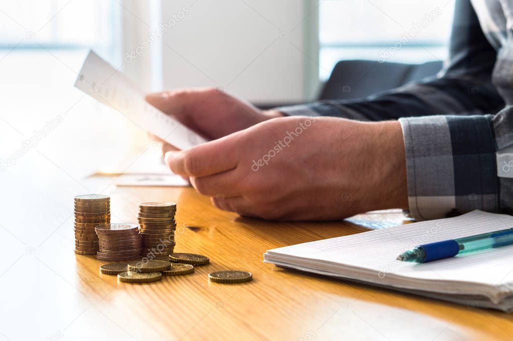 Man reading bank statement, check reminder, tax refund document, phone bill, or financial letter. Home or health insurance price and cost concept. Person holding paper invoice in hand.